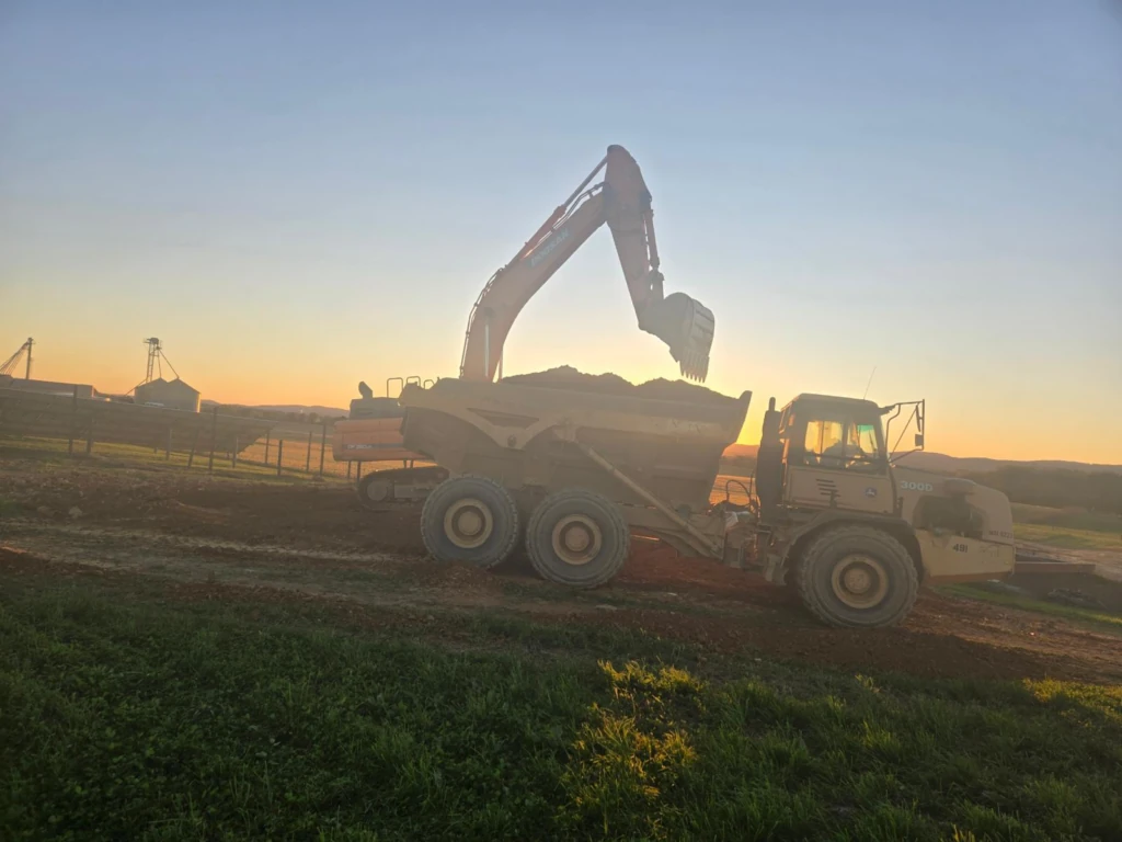 Excavator loading cleared debris into a dump truck during lot clearing in Annapolis, MD